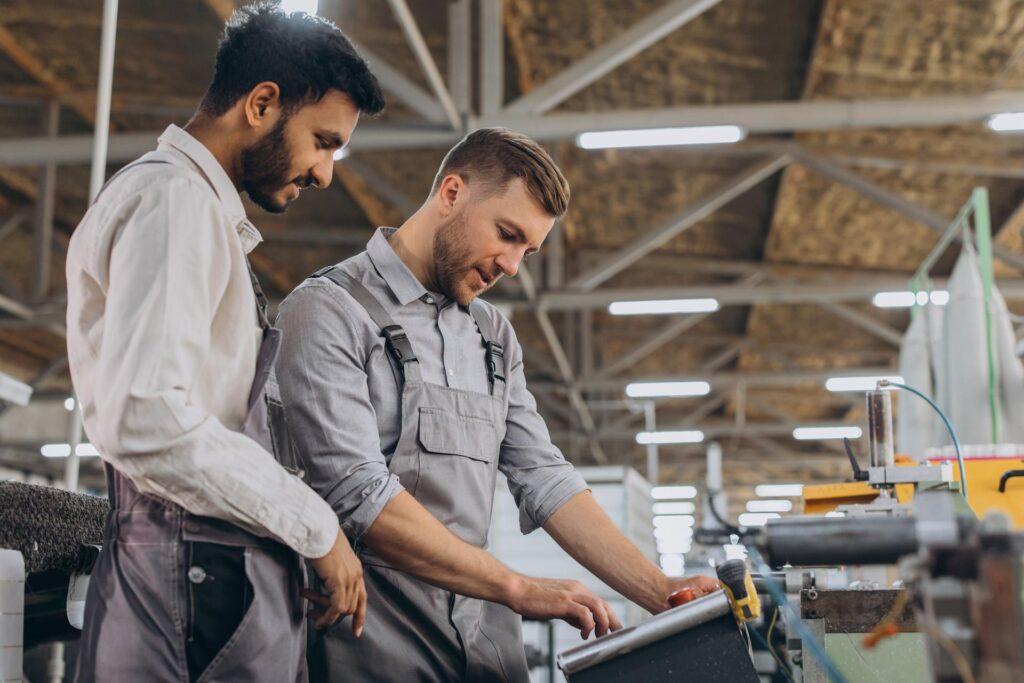 Ein männlicher Inspektor oder Bediener einer Werkstatt für die Herstellung von Aluminium- und Kunststoffkränzen weist einen Praktikanten ein.