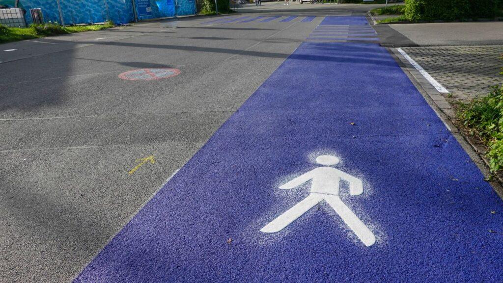 Lila beschichteter Fussweg mit Symbol auf Asphalt – klare Struktur durch gezielte Straßenmarkierung im Verkehrsbereich