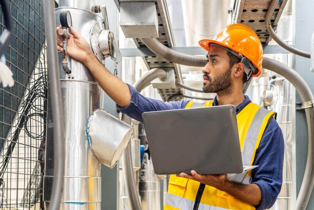 Ingenieur kontrolliert Industrieanlage mit Laptop | Schleifringkörper