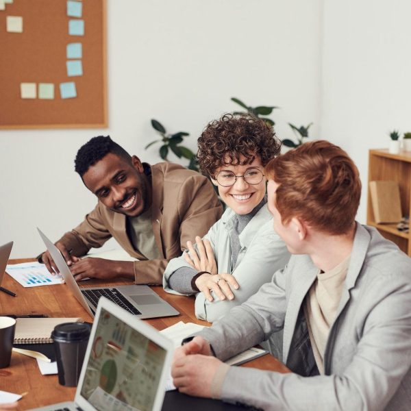 Drei Mitarbeiter an einem Tisch mit Laptops in einem Unternehmen